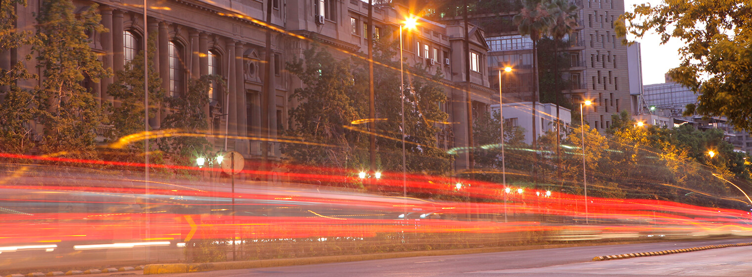 Una calle con las luces de los autos difuminadas, con un edificio al fondo